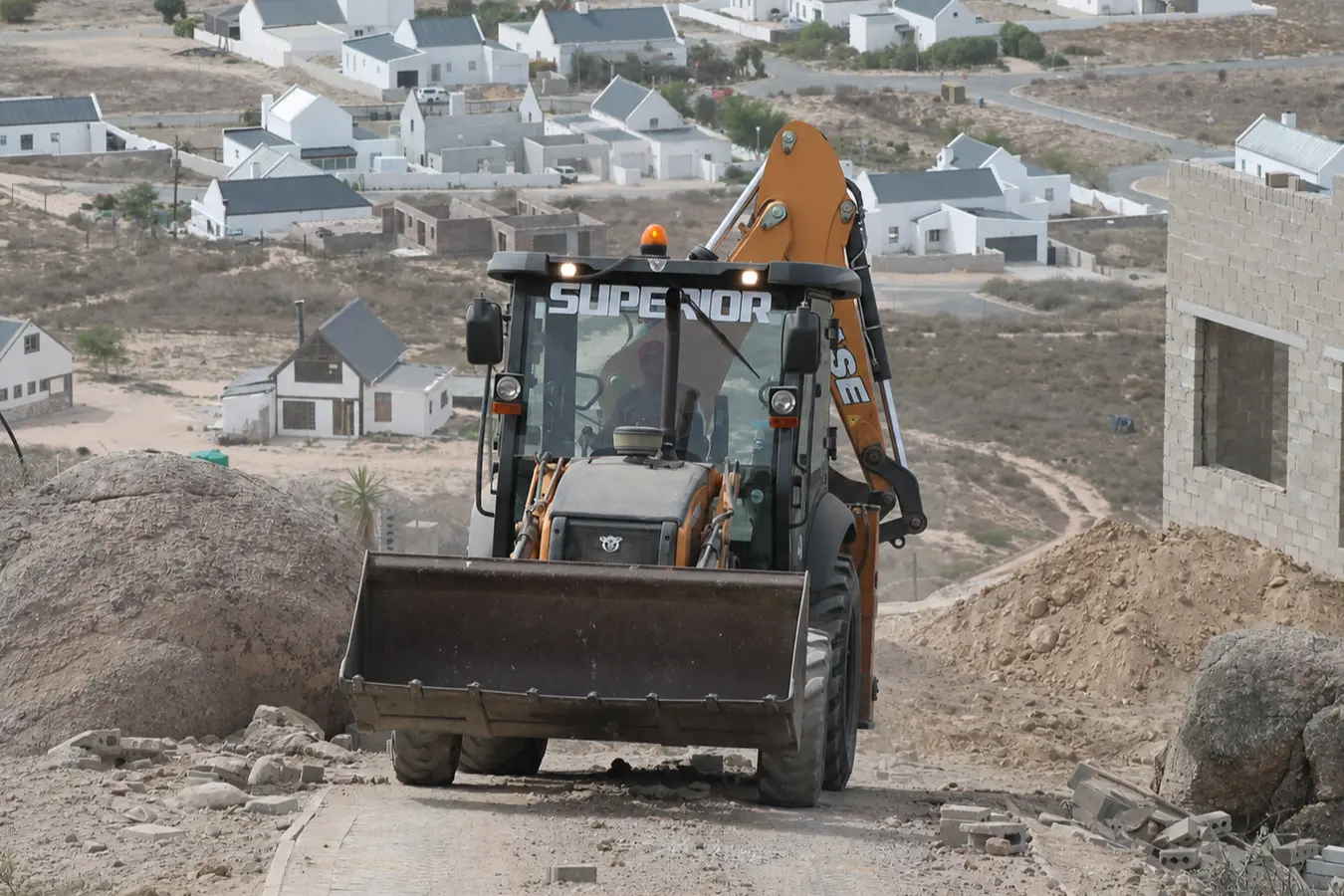 Digger loader working on an elevated site with a mountain view