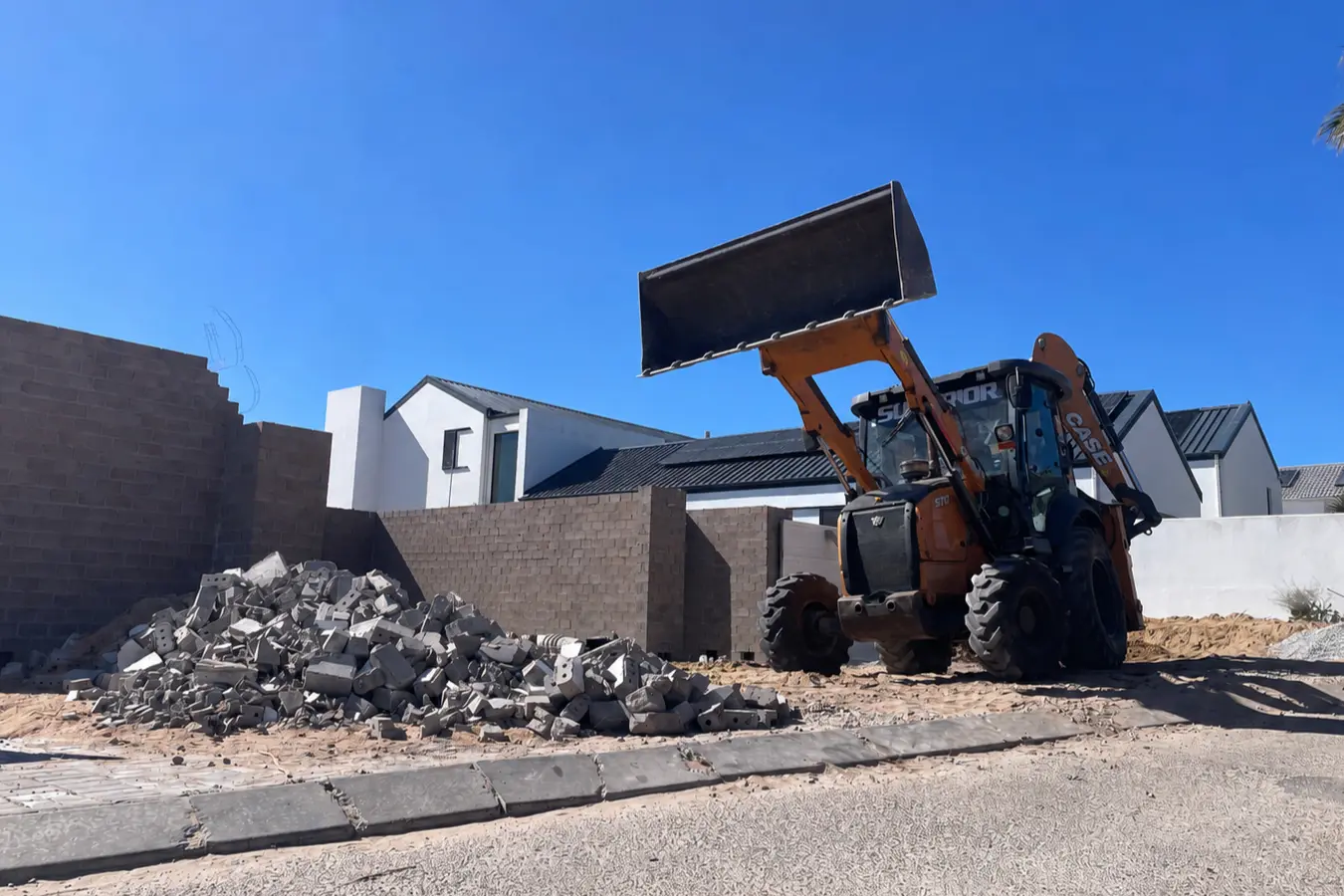 Digger loader clearing a pile of rubble on site